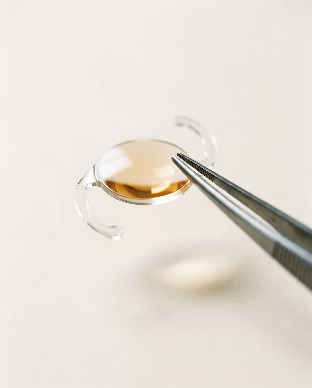Lente intraocular usada na cirurgia de catarata, segurada por uma pinça